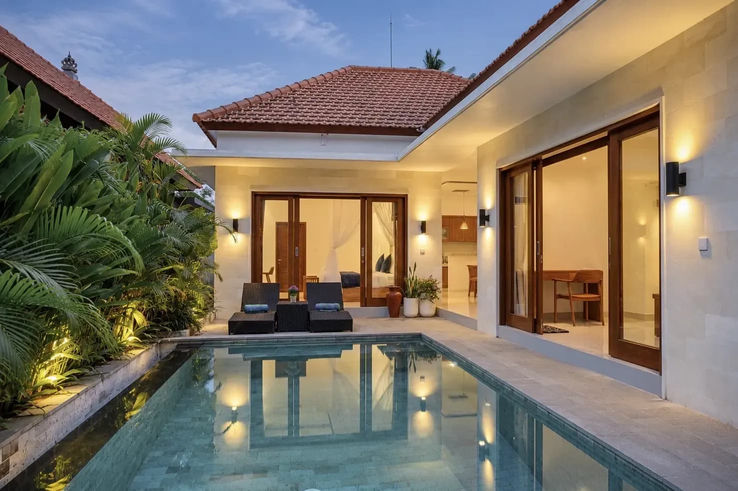 Die Villa Cahyana Tibuah erleuchtet in der Abenddämmerung neben dem Pool