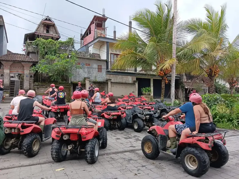 A group riding ATV quad bikes on a muddy jungle trail in Bali