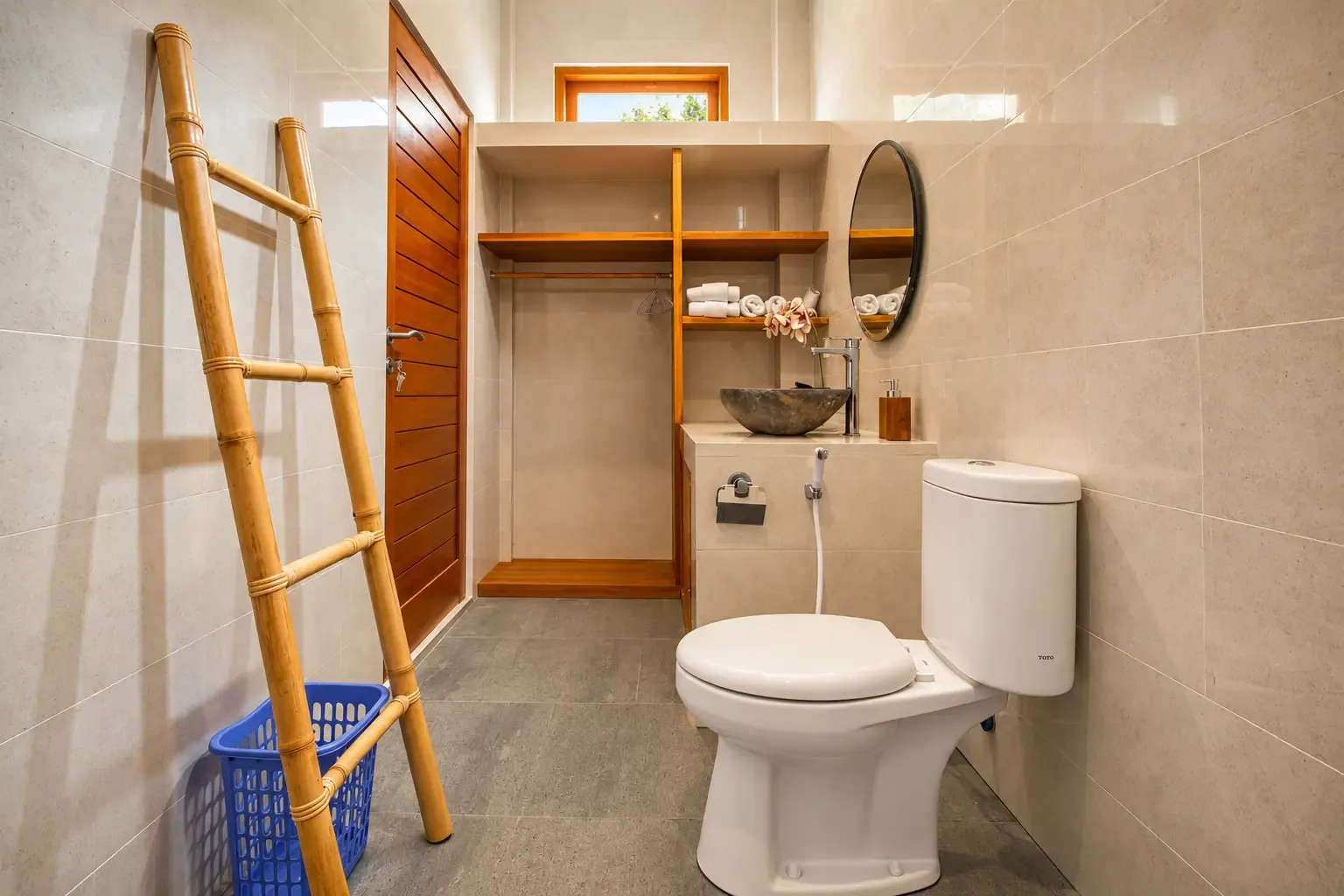 Baño Cahyana House con escalera de bambú para toallas y estantes abiertos.