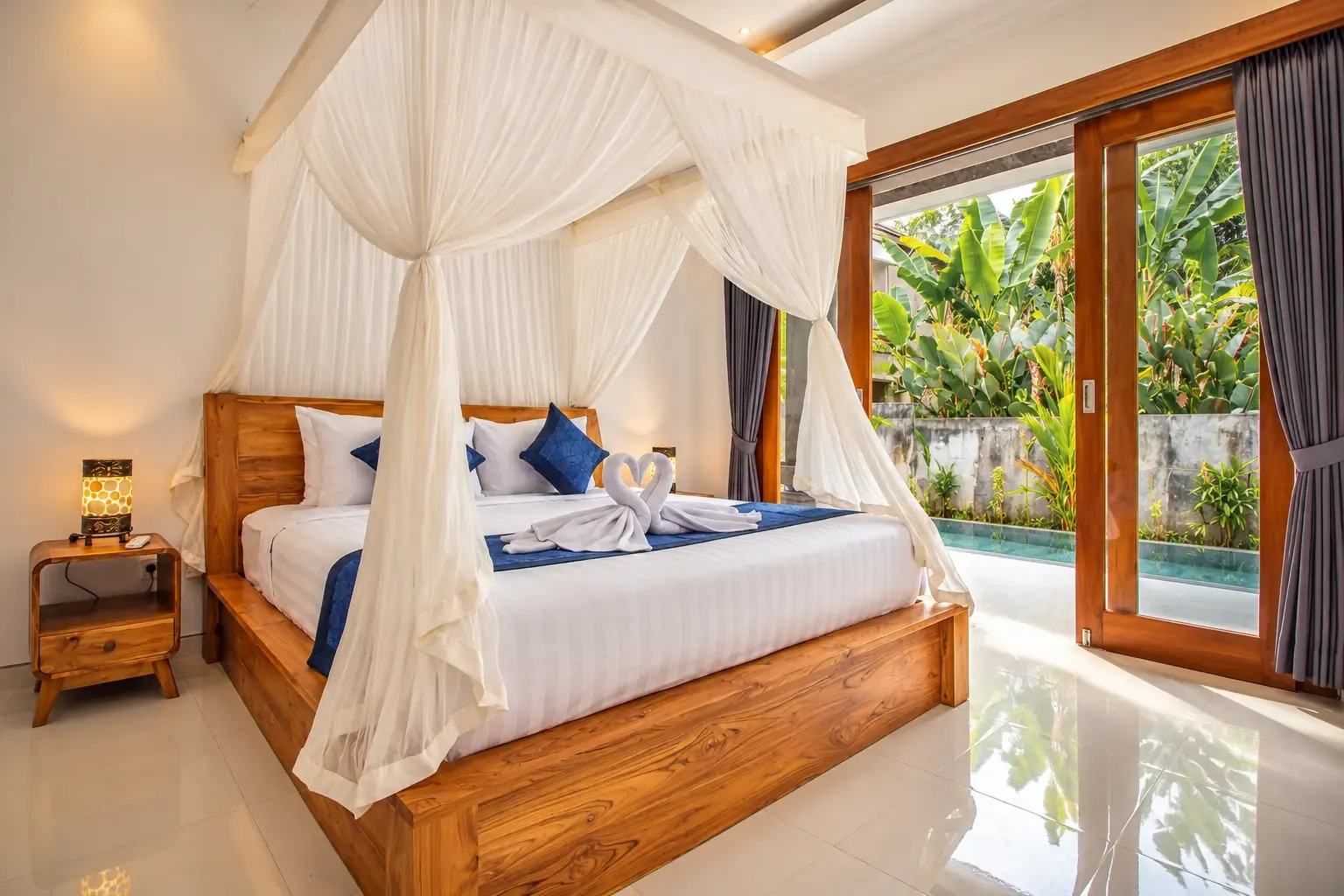 Cama con dosel Cahyana House con puertas de cristal que dan al jardín.