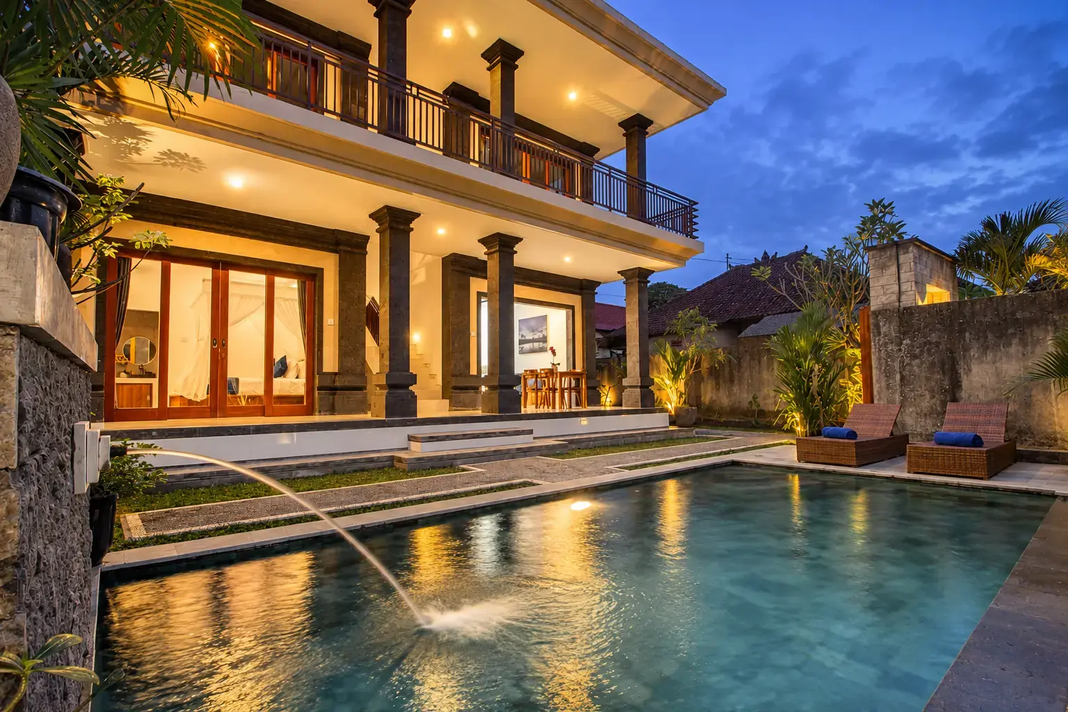 La piscina Cahyana House con el surtidor de agua de piedra al atardecer.