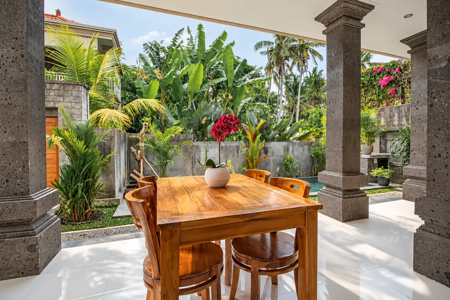 Mesa de comedor de teca Cahyana House en la terraza al aire libre.
